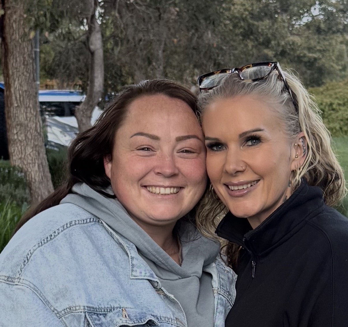 Two women smiling warmly together outdoors, supporting mental health and community wellbeing