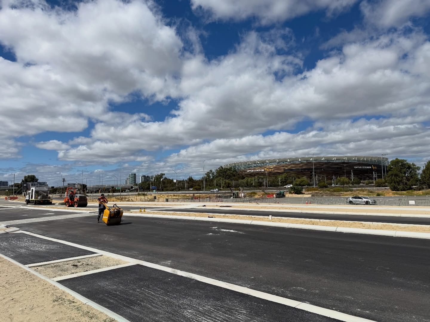 SuperCivil freshly laid asphalt car park and roads with line marking near Perth's Optus Stadium, with a roller compacting the surface