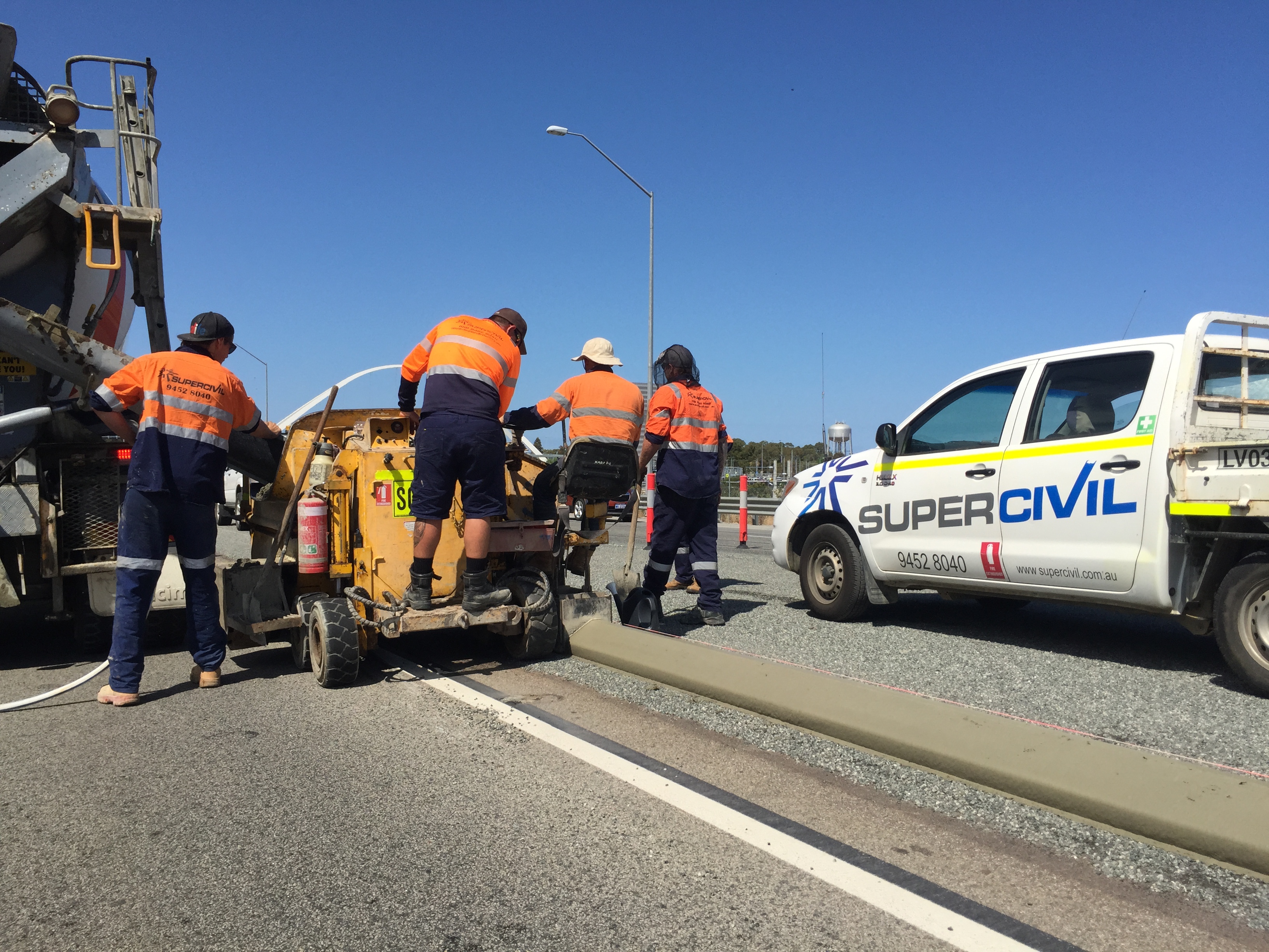 SuperCivil crew operating an extruded kerbing machine and laying continuous concrete kerb along a highway edge on a local government road project in Western Australia