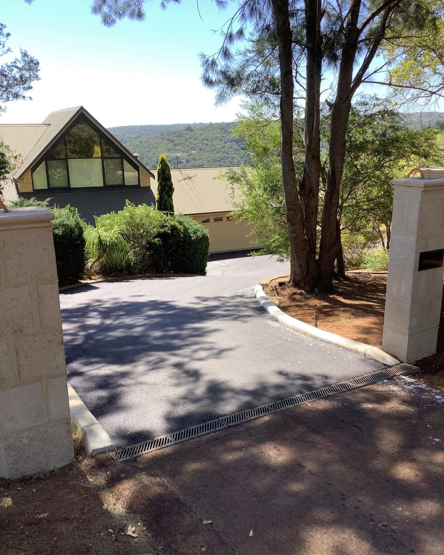 Residential asphalt driveway with concrete mountable kerb edging and limestone gate pillars in the Perth Hills