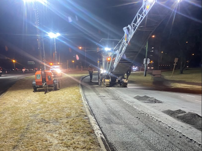 SuperCivil night-time road profiling operation under floodlights, with a cold-milling machine removing the road surface and hi-vis crew on a Western Australian road