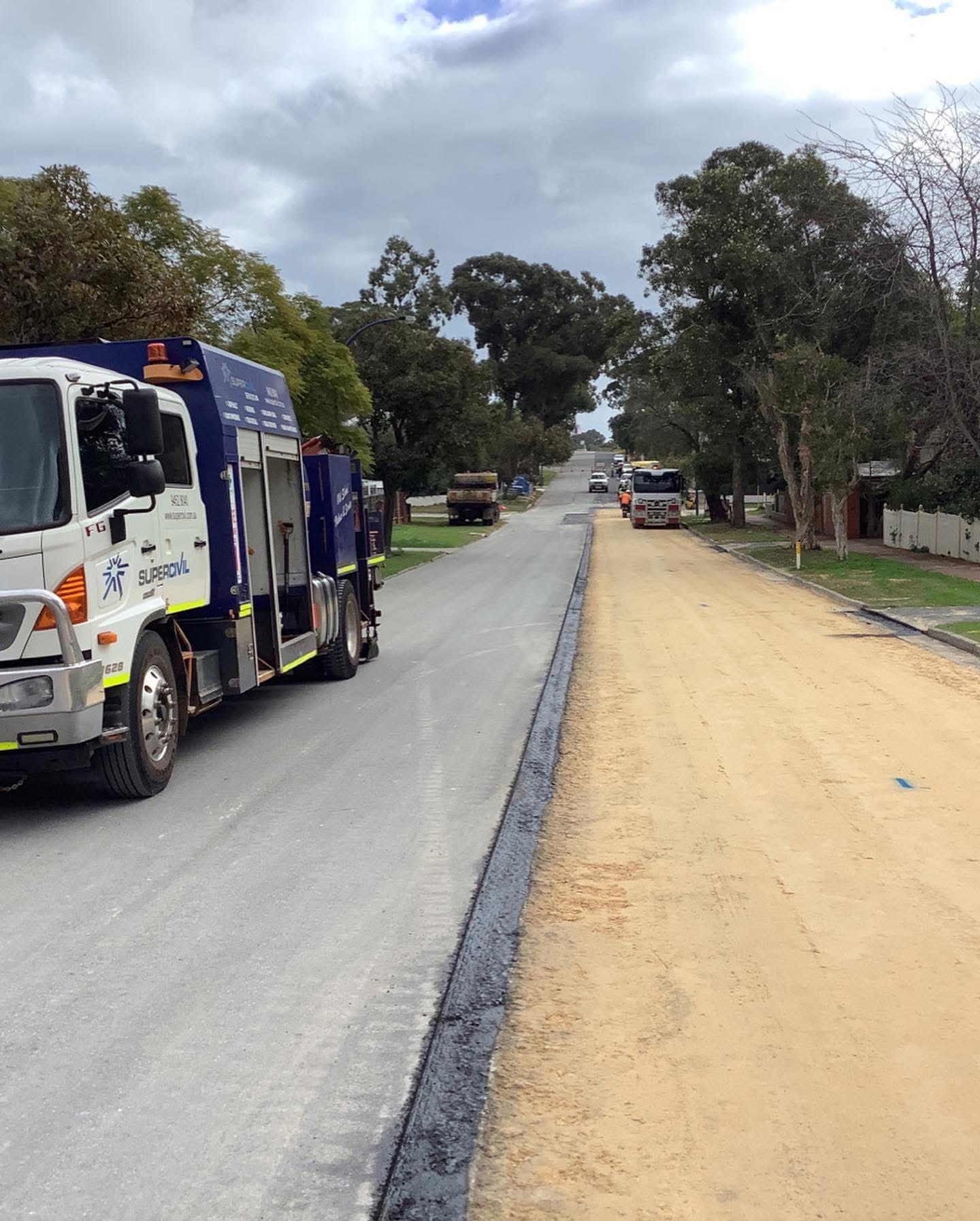 SuperCivil service truck on a suburban Western Australian street during road reconstruction, with one lane freshly sealed in new asphalt and the other stripped back to sand base